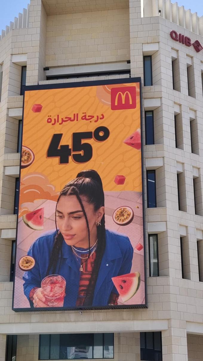 The Arabic McDonald's board live on a Doha tower reading درجة الحرارة ٤٥°, with the logo mirrored to the top right and the numerals set in Eastern Arabic.